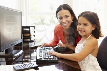 Hispanic mother and daughter using computer at home