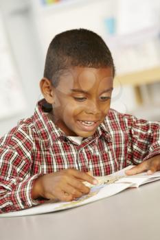 Elementary Age Schoolboy Reading Book In Class 