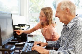 Senior man and granddaughter using computer