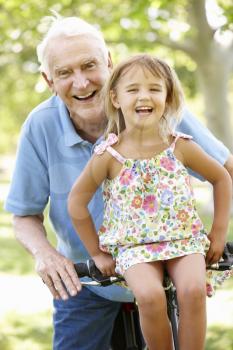 Senior man riding bike with granddaughter