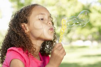 Young African American Girl Blowing Bubbles In Park