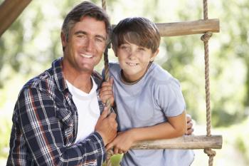 Father And Son In Garden By Treehouse