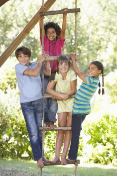 Group Of Children Climbing Rope Ladder To Treehouse