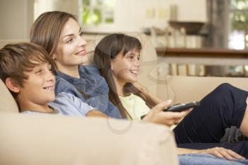 Mother And Two Children Sitting On Sofa At Home Watching TV Together