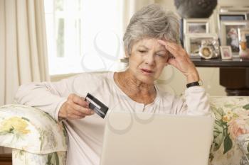 Frustrated Retired Senior Woman Sitting On Sofa At Home Using Laptop