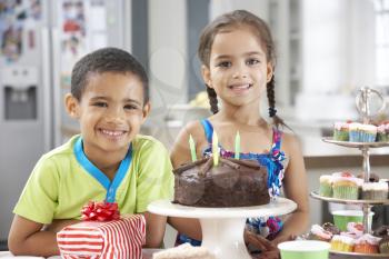Two Children Standing By Table Laid With Birthday Party Food