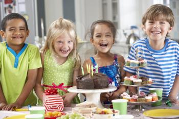 Group Of Children Standing By Table Laid With Birthday Party Food