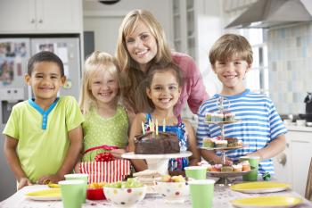 Group Of Children Standing With Mother By Table Laid With Birthday Party Food