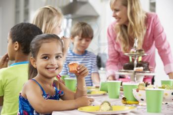 Group Of Children Enjoying Birthday Party Food At Table
