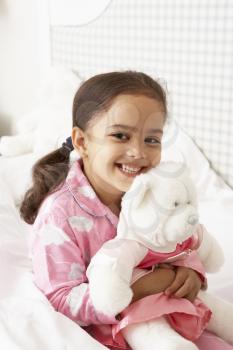 Young Girl Wearing Pajamas In Bed With Cuddly Toy