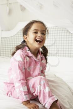 Young Girl Wearing Pajamas Sitting On Bed
