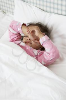 Tired Young Girl Wearing Pajamas In Bed