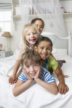 Four Children Playing On Bed Together