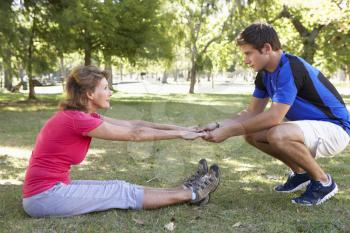 Senior Woman Working With Personal Trainer In Park