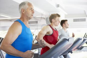 Group Of Men Using Running Machines In Gym