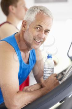 Man On Running Machine In Gym Drinking Water