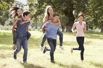 Group Of Young Friends Running Through Countryside