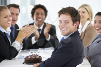 Portrait Of Male Executive Celebrating Birthday In OfficeWith Colleagues