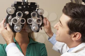Optician In Surgery Giving Woman Eye Test