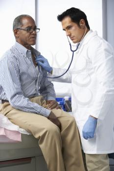 Doctor In Surgery Listening To Male Patient's Chest