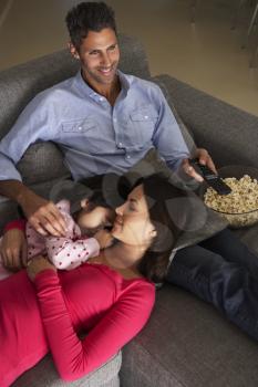 Hispanic Family On Sofa Watching TV And Eating Popcorn
