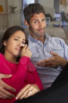 Hispanic Couple On Sofa Watching Sad Movie On TV