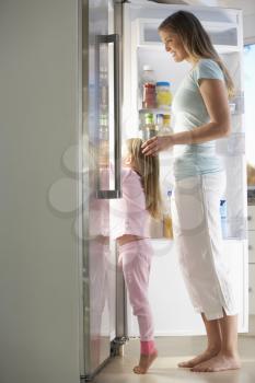Mother And Daughter Choosing Snack From Fridge