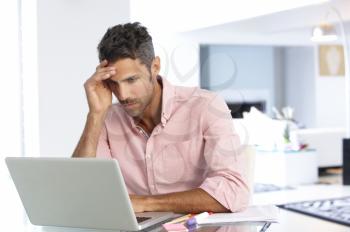 Stressed Man Working At Laptop In Home Office
