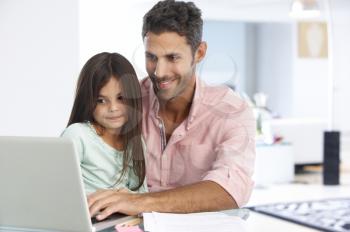 Man Working At Laptop With Daughter In Home Office