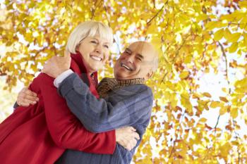 Senior Couple Hugging Underneath Autumn Tree
