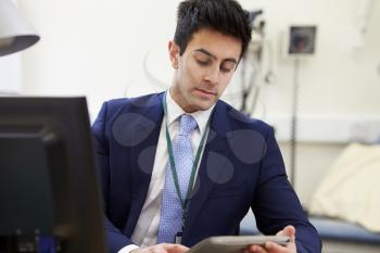 Male Consultant Working At Desk Using Digital Tablet