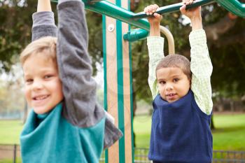 Two Young Boys On Climbing Frame In Playground