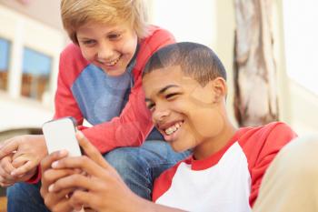 Two Teenage Boys Reading Text On Mobile Phone