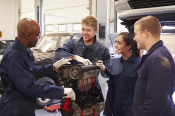 Teacher Helping Students Training To Be Car Mechanics