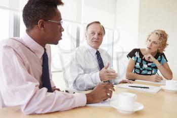 Three Businesspeople Having Meeting In Boardroom