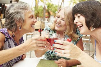Senior Female Friends Enjoying Cocktails In Bar Together