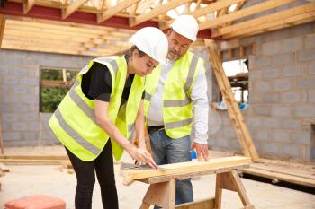 Carpenter With Female Apprentice Working On Building Site