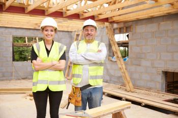 Carpenter With Female Apprentice Working On Building Site