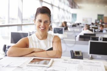 Female architect at her desk, smiling to camera