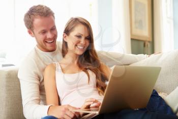 Couple Relaxing On Sofa Using Laptop Computer Together