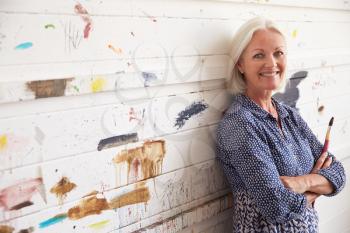 Portrait Of Female Artist Against Paint Covered Wall