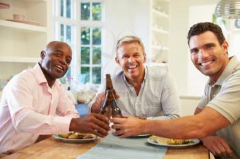 Mature Male Friends Sit At Table Drinking Beer And Eating
