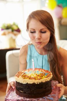 Young Woman Blowing Out Candle On Birthday Cake