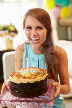 Portrait Of Young Woman Blowing Out Candle On Birthday Cake