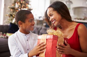 Mother Giving Christmas Presents To Son At Home