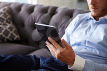 Close Up Of Man Sitting On Sofa Using Digital Tablet