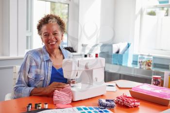 Senior black woman using a sewing machine looking to camera