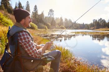 Man relaxing and fishing by lakeside, California, USA
