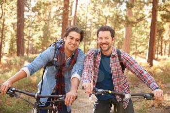 Portrait Of Gay Male Couple Cycling Through Fall Woodland