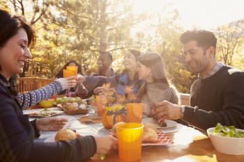 Group of happy friends eat and drink at a table at a barbecue